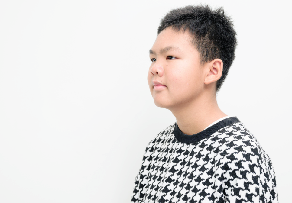 옆모습으로 찍힌 어린이의 얼굴과 상반신 모습. 흰색 배경에 검은색과 흰색 패턴의 옷을 입고 있다.